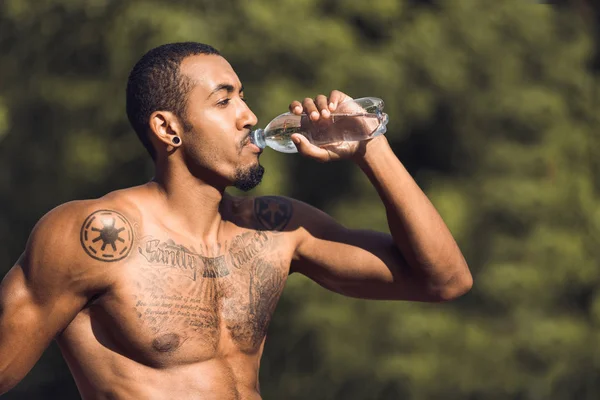 Atletický muž pitné vody po cvičení venku — Stock fotografie