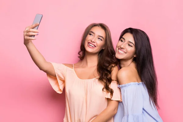Dos mujeres alegres tomando selfie sobre fondo rosa —  Fotos de Stock
