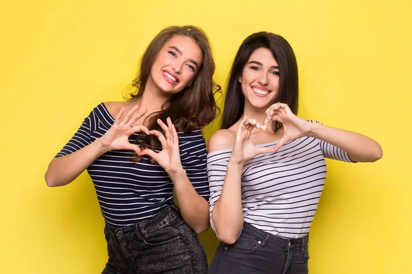 Mujeres alegres dando forma a las manos como corazones en la cámara —  Fotos de Stock