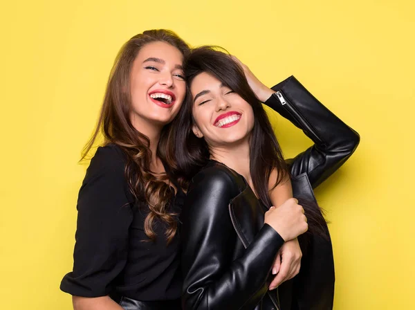Две красивые девушки обнимаются на жёлтом фоне — стоковое фото