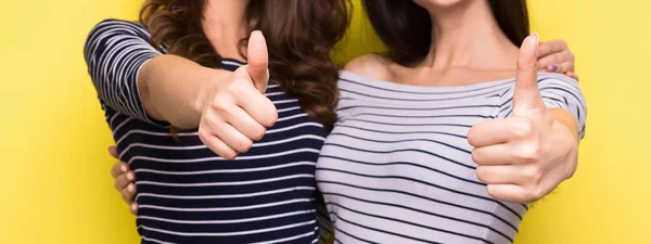 Mujeres mostrando pulgares hacia arriba sobre fondo amarillo —  Fotos de Stock