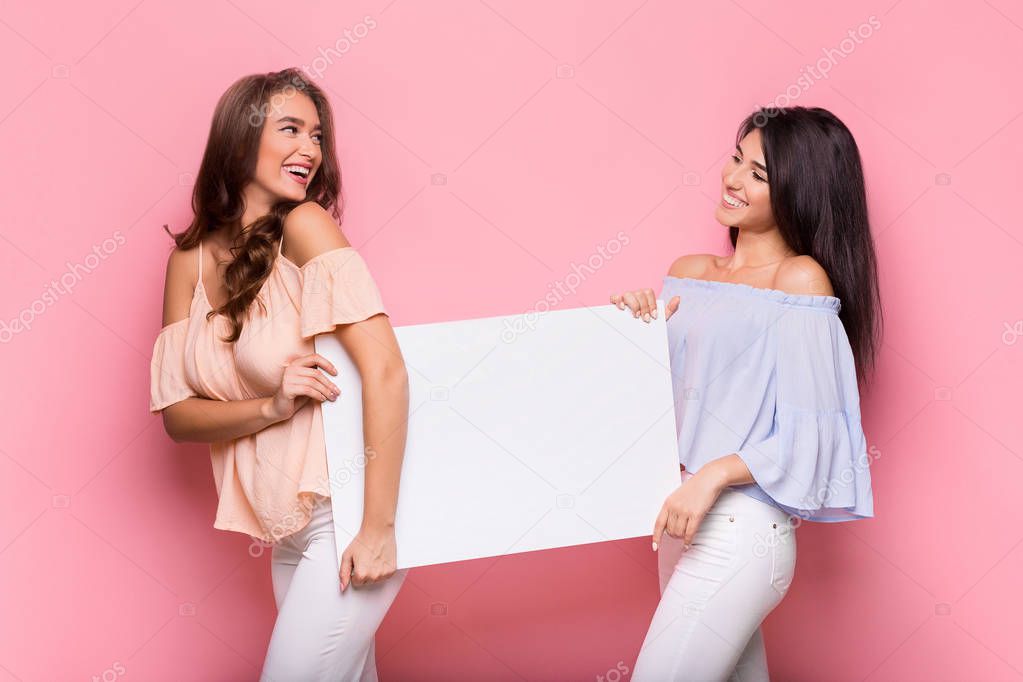 Happy girl friends holding blank advertisement board