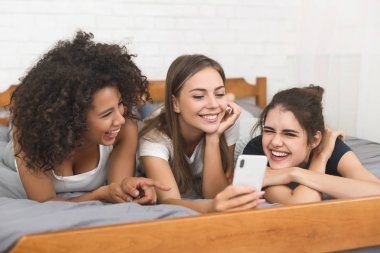 Genç kız yatakta yatarken smartphone ile