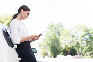 İşkadını smartphone üzerinde araç açık havada yaslanmış, kontrol