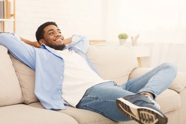 Bonito homem africano-ameriacn relaxando no sofá em casa — Fotografia de Stock