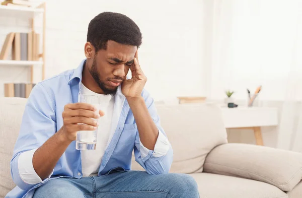 Hombre afroamericano con dolor de cabeza tomando píldora en casa — Foto de Stock