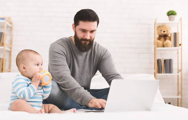 Dad browsing on laptop and watching his baby — Stock Photo, Image