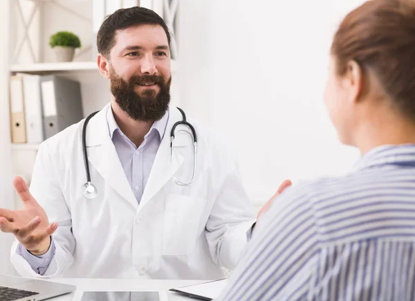 Усміхнений лікар розмовляє з пацієнтом в офісі — стокове фото