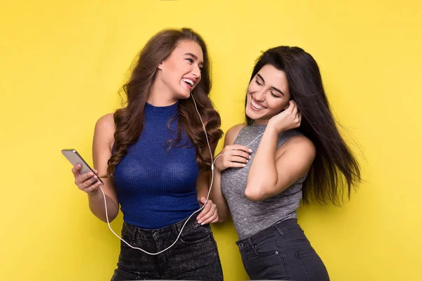 Dos mujeres escuchando música en línea en el smartphone — Foto de Stock