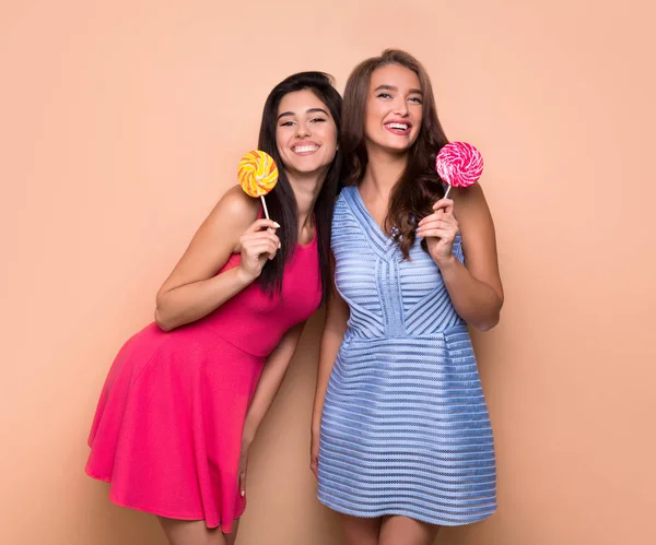 Dos atractivos amigos de lujo sosteniendo piruletas de colores — Foto de Stock