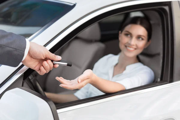 Car dealer giving keys to happy female customer