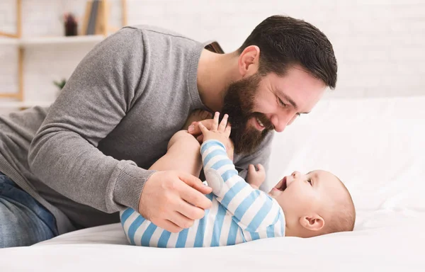Отец щекочет и обнимает своего маленького сына — стоковое фото