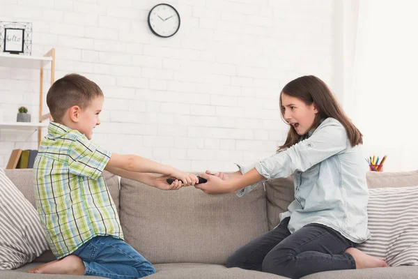 Bror och syster slåss om fjärrkontrollen hemma — Stockfoto