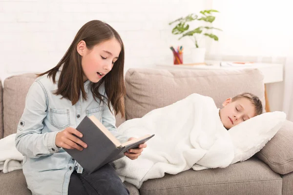 Chica leyendo cuento de hadas a pequeño hermano enfermo —  Fotos de Stock