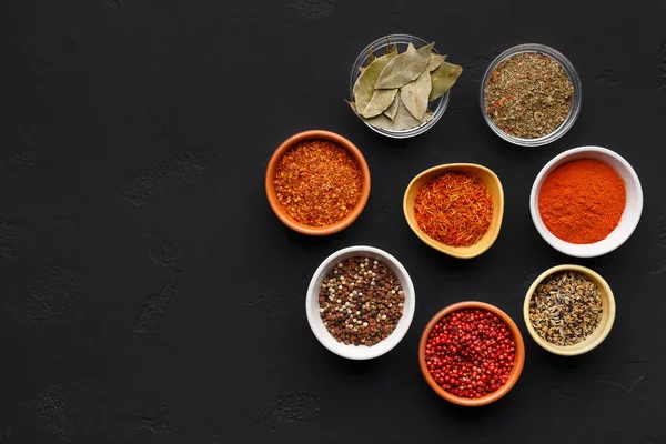 Colourful spices in bowls on black background — Stock Photo, Image