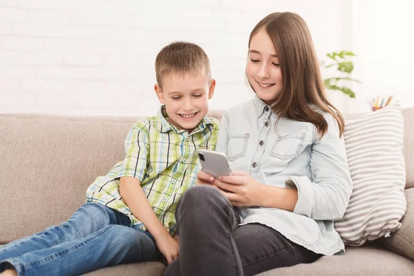 Hermana y hermano viendo dibujos animados en el teléfono inteligente juntos —  Fotos de Stock