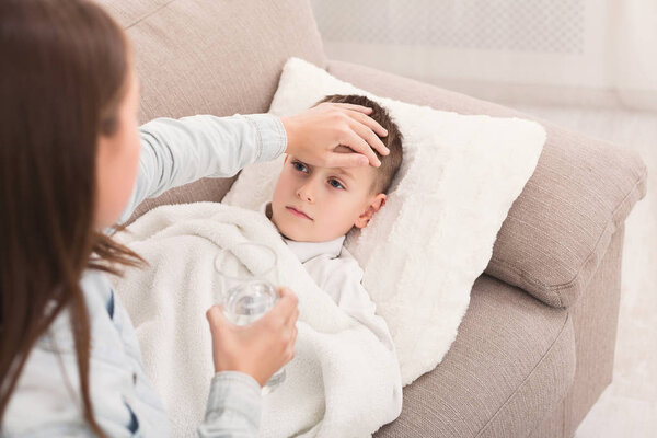 Sister touching her brothers forehead, checking temperature