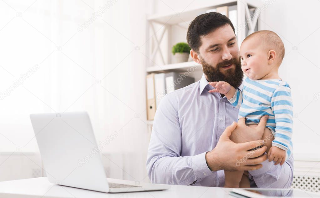 Business dad working in office with baby son
