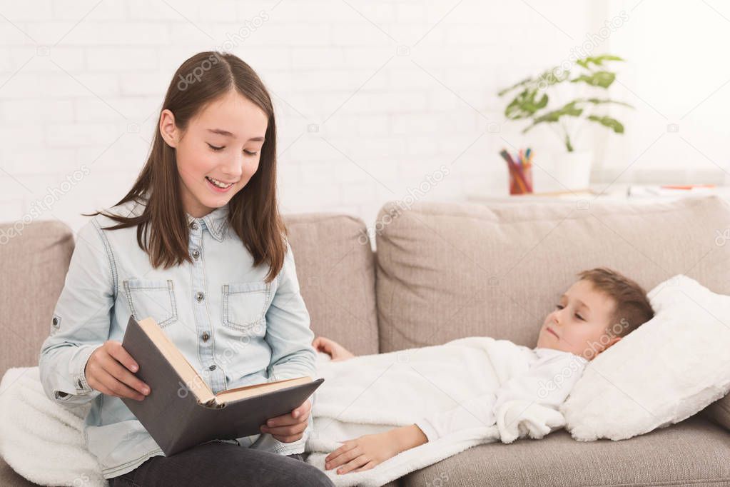 Girl reading book to little sick brother