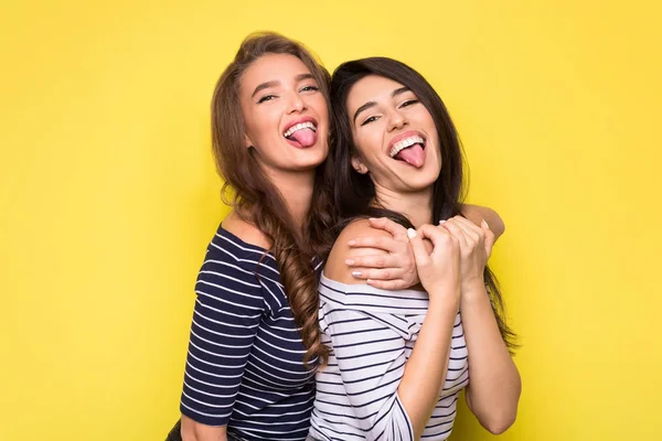 Retrato de estilo de vida de dos mujeres bonitas mostrando la lengua . —  Fotos de Stock