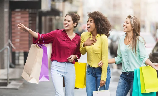 Mulheres felizes com sacos de compras andando ao longo da rua da cidade — Fotografia de Stock