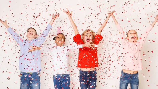 Gelukkige kinderen gooien van confetti tegen de lichte achtergrond — Stockfoto