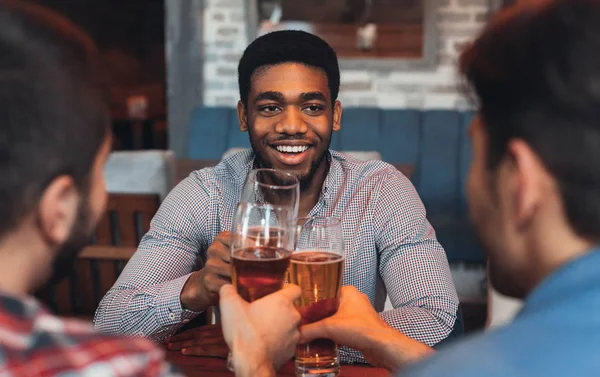 Три чоловіки п'ють пиво, святкуючи зустріч у барі — стокове фото