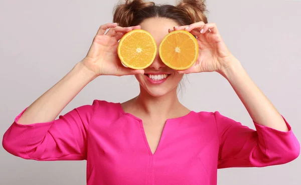 Mulher engraçada segurando metades de laranjas contra fundo — Fotografia de Stock