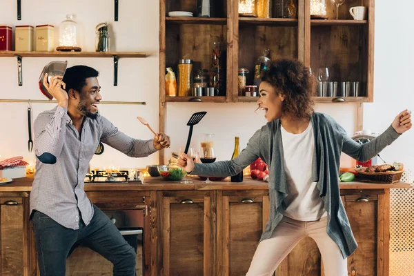 Divertida pareja luchando con utensilios herramientas en la cocina —  Fotos de Stock