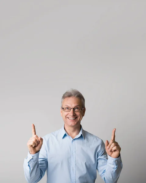 Happy mature man pointing up at copy space — Stock Photo, Image