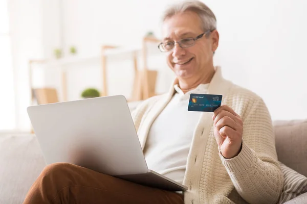Зрілий чоловік купує онлайн на ноутбуці з кредитною карткою — стокове фото
