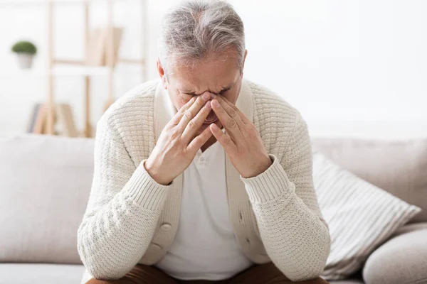Senior leidet unter Kopfschmerzen, sitzt auf Sofa — Stockfoto