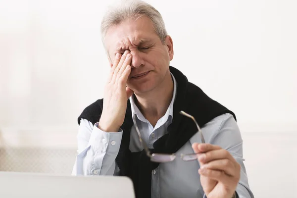 Frustrado homem maduro olhando esgotado, trabalhando no laptop — Fotografia de Stock
