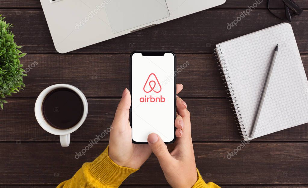 KHARKOV, UKRAINE - December 23,2018: Woman using Airbnb application on Iphone X. Airbnb is website for people to list, find, and rent lodging.