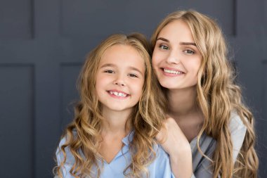 Neşeli anne ve kızı kameraya gülümseyen