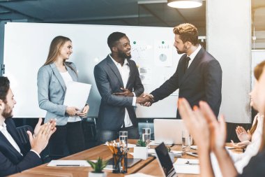 Genç erkekler tokalaşırken yönetim kurulu odasında