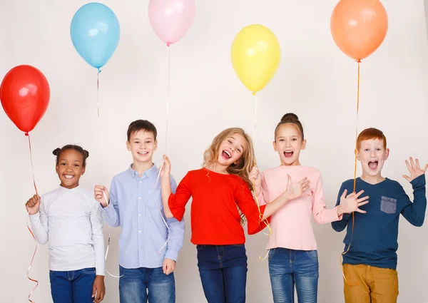 Bambini felici con palloncini colorati sopra la parete — Foto Stock