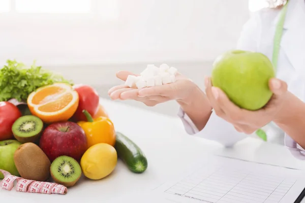 Médico sosteniendo cubos de manzana y azúcar en las manos — Foto de Stock