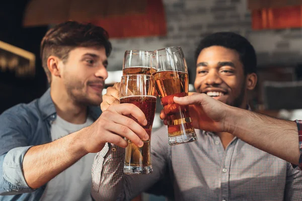 Mužských přátel popíjí pivo a cinkání brýle na baru — Stock fotografie