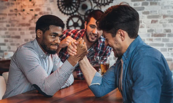 Hombres amigos brazo de lucha libre entre sí en el bar — Foto de Stock