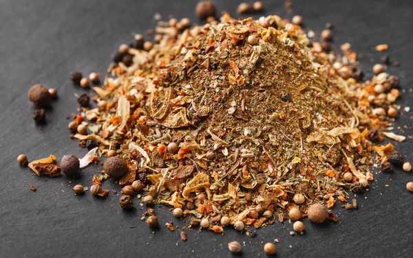 Mix of spices, herbs and peppercorns on dark board Stock Image