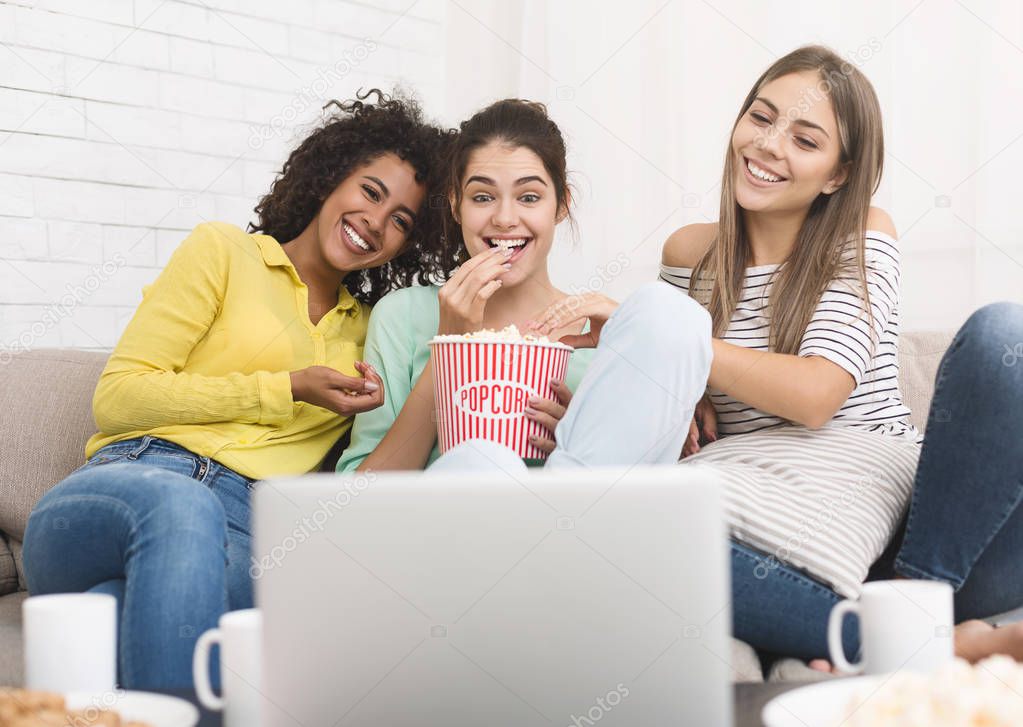 Girls watching comedy movie and eating popcorn at home
