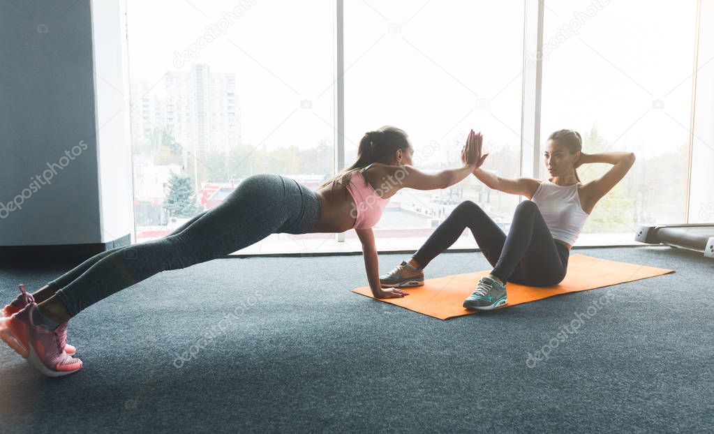 Two girls training together in modern gym