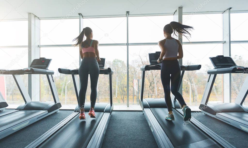 Sports people running on treadmills, looking out the window