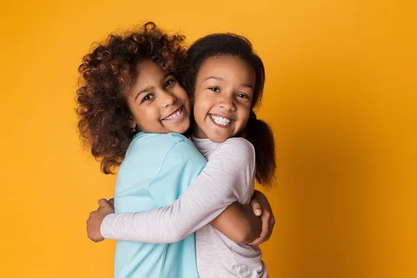 Niñas abrazando y riendo sobre fondo amarillo — Foto de Stock