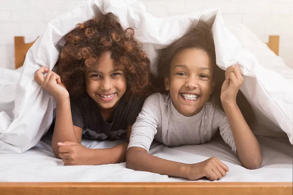 Afro-americké dítě dívky ležící pod deku na postel — Stock fotografie