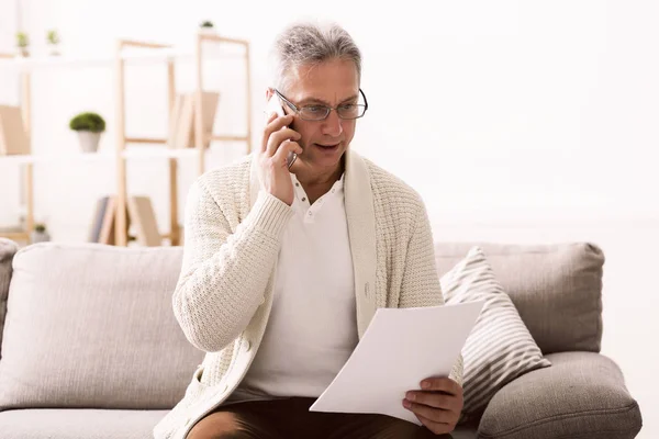 Diskussionsgrundlage. Reifer Mann hält Papier und telefoniert — Stockfoto