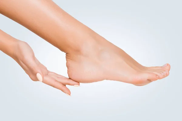 Woman touching her soft heel skin on blue background — Stock Photo, Image