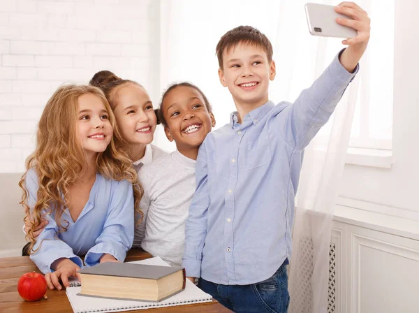 Niños felices tomando selfies en el aula de la escuela —  Fotos de Stock