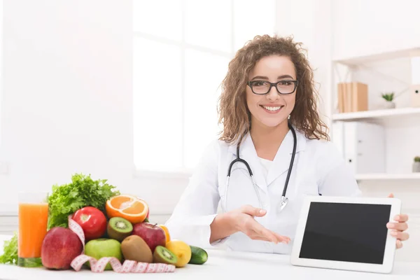Médecin nutritionniste avec légumes et fruits tenant tablette numérique vierge — Photo
